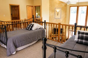 A bedroom with two beds, a wooden railing, a television, and a wall-mounted light fixture. - Roomy Beautiful Golf/Ski Condo (Clymer)