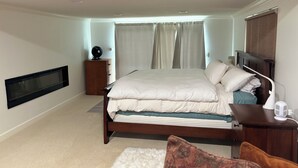 A bedroom with a bed, bedside table, nightstand, and a wall-mounted TV.