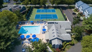 An aerial view of a residential area with a tennis court, swimming pool, and lounge chairs. - Coastal Retreat - 2BR CONDO (Rehoboth Beach)
