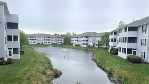 A residential area with multi-story apartment buildings, a small water feature, and well-maintained lawns. - Coastal Retreat - 2BR CONDO (Rehoboth Beach)