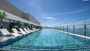 A modern infinity pool with clear blue water, surrounded by a glass railing and white lounge chairs. - Ocean House in The Song An Gia Vung Tau (Ho Chi Minh City)