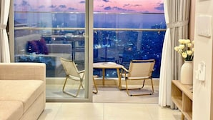 A modern living room with a large window, two chairs, a small table, and a sofa. - Ocean House in The Song An Gia Vung Tau (Ho Chi Minh City)