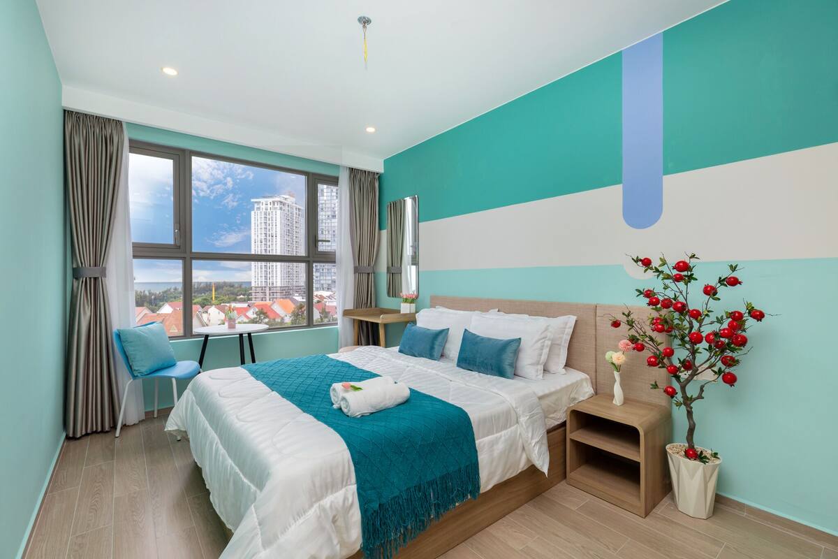 Une chambre d’hôtel moderne avec un grand lit, une vue sur la ville et une plante décorative.