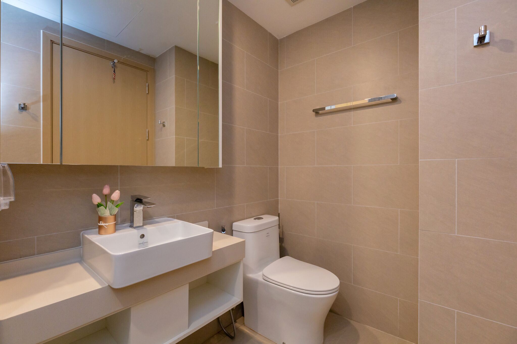 Une salle de bain moderne avec un lavabo, des toilettes et un miroir, le tout de couleur blanche.