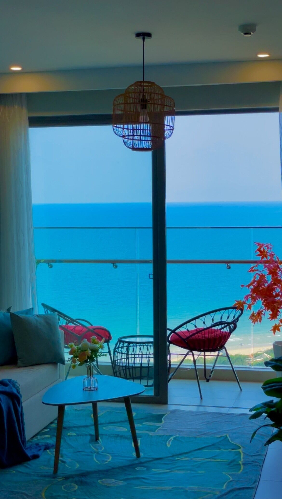 Un balcon avec vue sur l’océan, un luminaire suspendu et un espace détente avec une table.