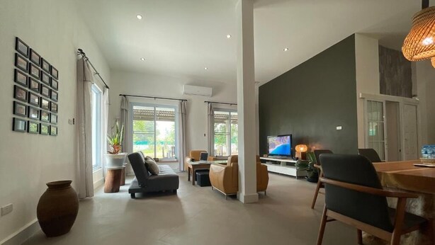 A spacious living area with a large TV, comfortable seating, and a dining table. - Salithyna villa (Vientiane)