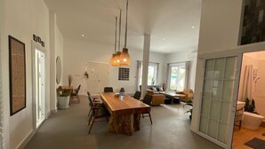 A spacious living area with a large wooden dining table, comfortable seating, and a modern chandelier. - Salithyna villa (Vientiane)