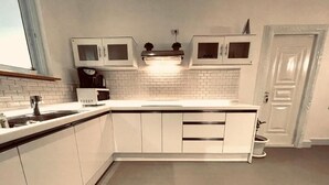 A modern kitchen with white cabinets, a microwave, and a sink. - Salithyna villa (Vientiane)