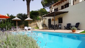 Ein Poolbereich mit Liegestühlen, einem Tisch und einer Pergola.