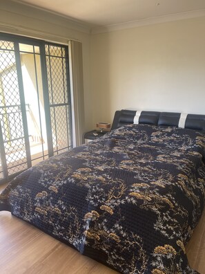 Un dormitorio con una cama grande, una mesita de noche y vistas a través de una puerta corredera.