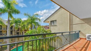 A balcony with a view of a swimming pool and palm trees. - Nearby Showgrounds and James St and King Williams Precints (Fortitude Valley)