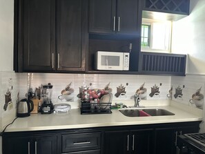 Una cocina con armarios oscuros, un microondas blanco y un salpicadero de azulejos con un diseño repetido.