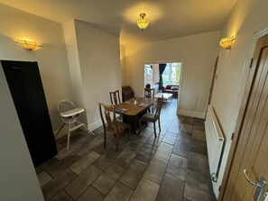 A dining area with a table, chairs, a high chair, and a refrigerator. - 2bed - garden-pets-freeparking-M1connections (Chesterfield)