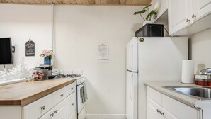 A compact kitchen with white cabinets, a wooden countertop, a stove, a refrigerator, and a sink. - Beach Bungalow, Free Parking, 2 blocks to the beach (San Diego)
