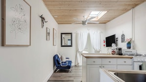 A kitchen with a stove, sink, and a ceiling fan. There is a blue chair and a white cabinet. - Beach Bungalow, Free Parking, 2 blocks to the beach (San Diego)