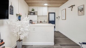 A modern kitchen with white cabinets, a central island, and a potted plant. - Beach Bungalow, Free Parking, 2 blocks to the beach (San Diego)