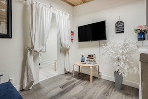 Relax in this serene space with a large flat-screen TV, a cozy reading nook, and a potted plant.