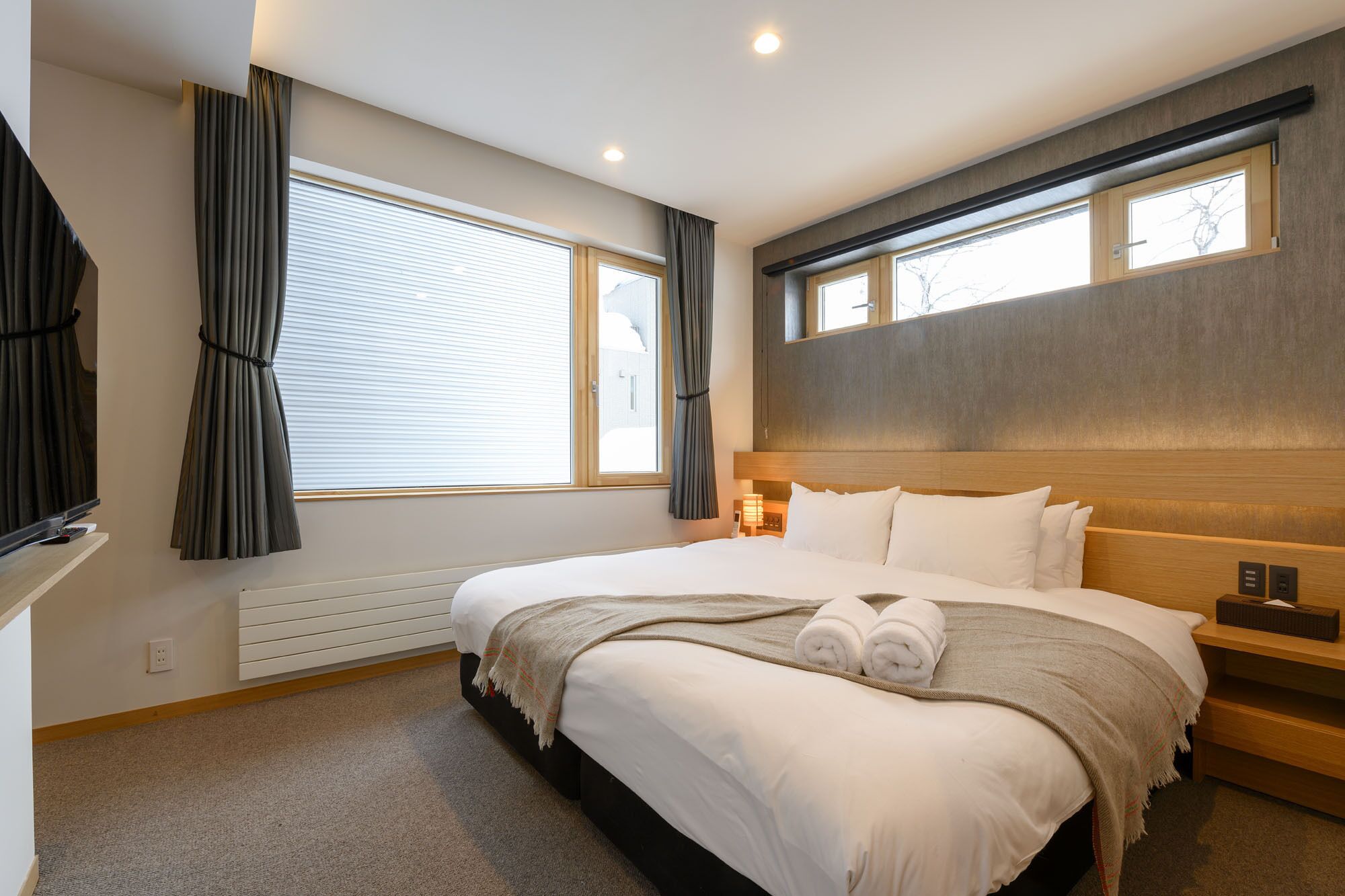Une chambre d’hôtel avec un grand lit, un téléviseur à écran plat, une table de chevet et une fenêtre avec des rideaux.