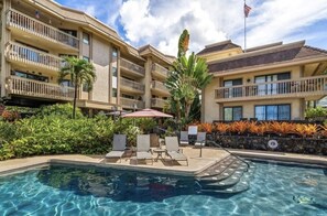 Relax by the pool surrounded by lush tropical plants and lounge chairs.