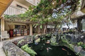 Stroll through this serene garden oasis, surrounded by a koi pond and lush greenery, with a cozy reading nook nearby.