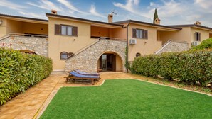 A two-story house with a stone facade, a small garden with a lawn and a bench, and a clear sky. - Pool House Kristina near Poreč, Kaštelir - Labinci, Croatia (Kaštelir - Labinci)
