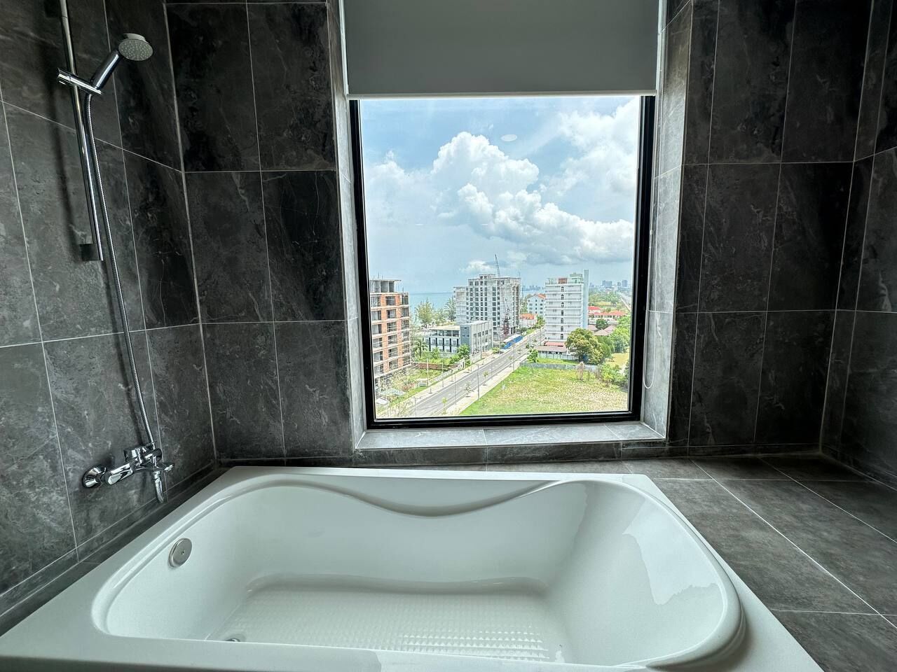 Ein modernes Badezimmer mit einer großen Badewanne, einer Dusche und einem Fenster mit Blick auf die Stadt.