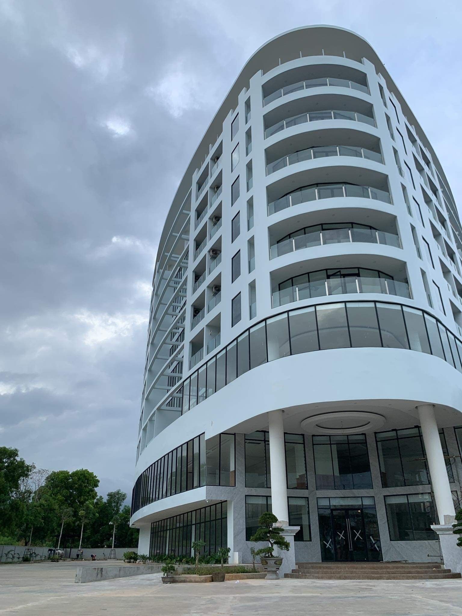 Un bâtiment moderne à plusieurs étages, doté d’une façade incurvée, de grandes fenêtres et d’une entrée centrale avec des marches.