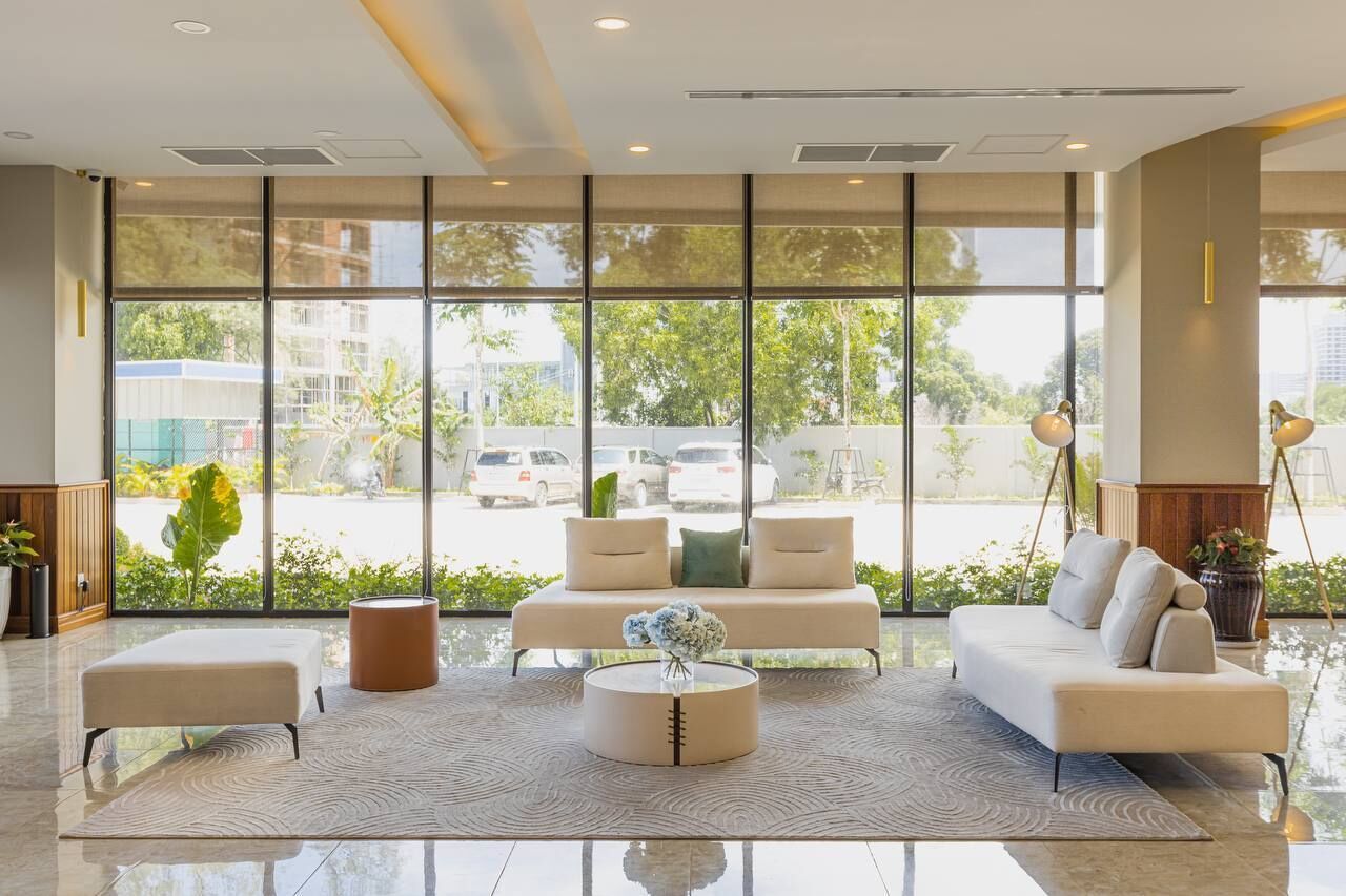 A modern hotel lobby with a large window, a sofa set, a coffee table, and a small side table.