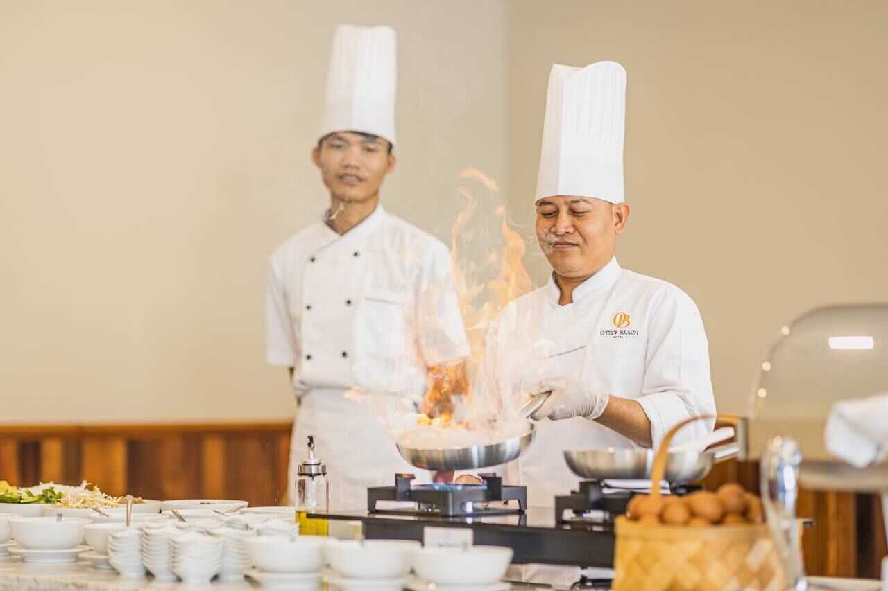 Chefs cooking with flames in a professional kitchen setting.