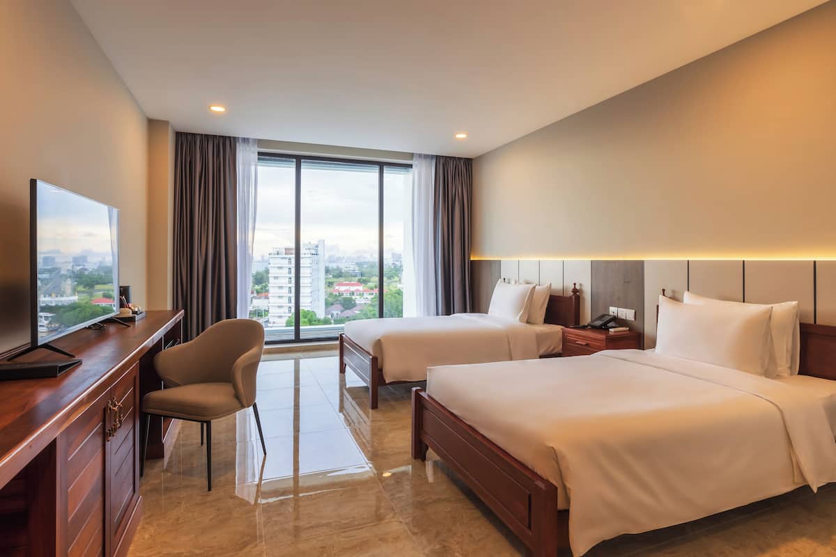 Une chambre d’hôtel avec deux lits, une télévision, un bureau et une chaise.