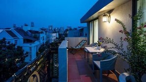 A balcony with a table and chairs, a potted plant, and a wall-mounted light fixture. - Kelly Hotel SECC Phu My Hung (Ho Chi Minh City)