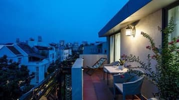 Un balcón con una mesa y sillas, una planta en maceta y un aplique de pared.