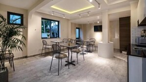 A modern hotel room with a dining area, a kitchen, and a large window providing a view of the outdoors. - Kelly Hotel SECC Phu My Hung (Ho Chi Minh City)