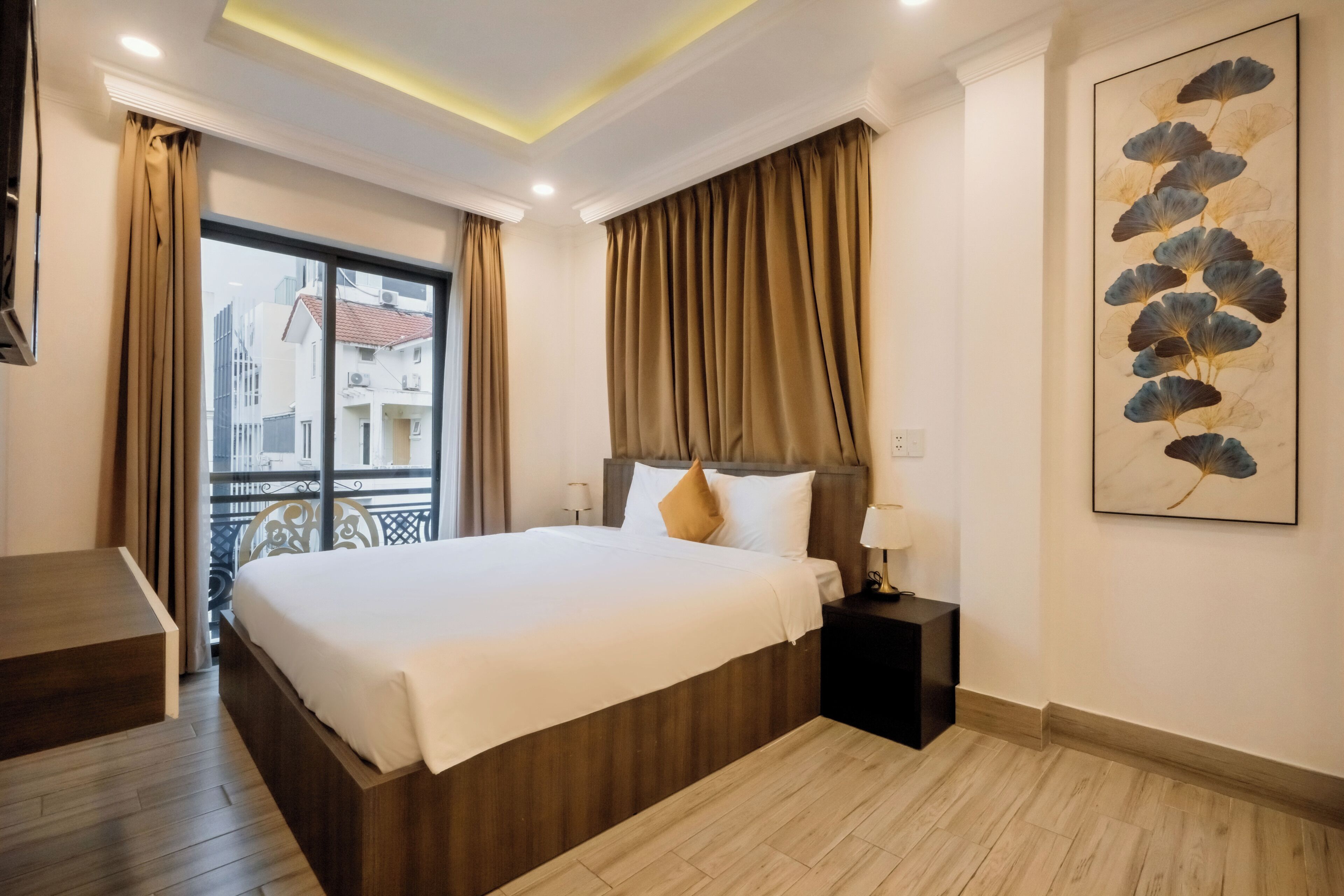 Une chambre d’hôtel avec un lit, une table de chevet, une lampe et une vue sur les immeubles par la fenêtre.