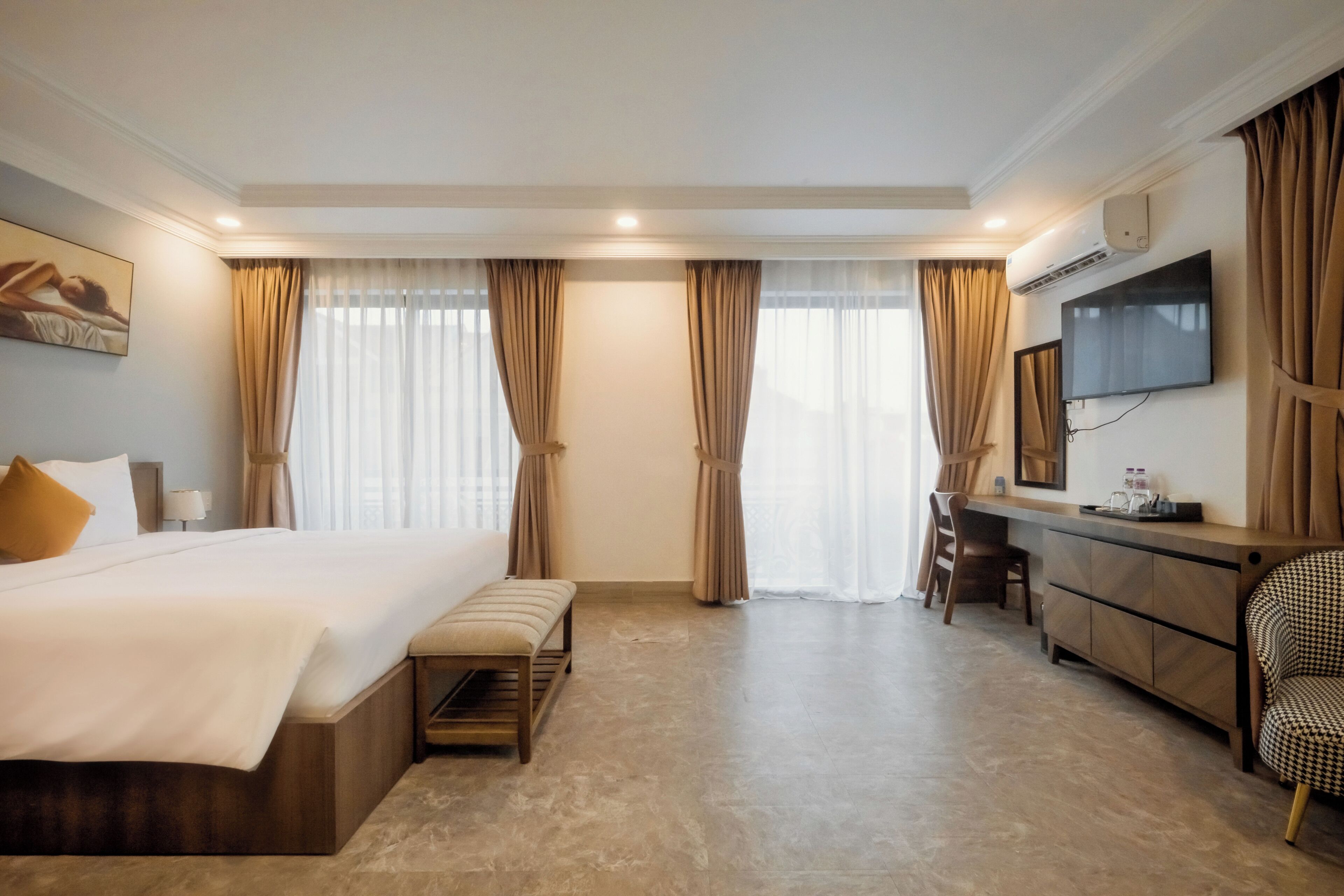 Une chambre d’hôtel avec un grand lit, un bureau, une chaise, une télévision et un tableau au mur.