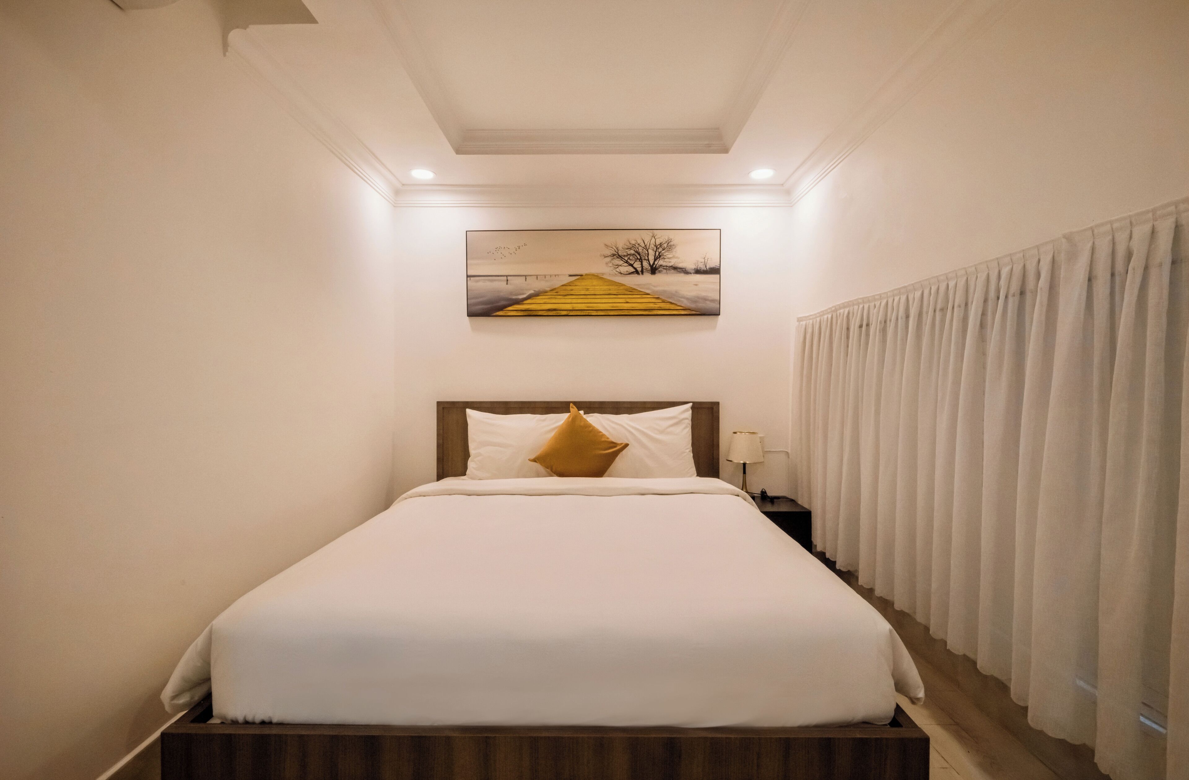 Una habitación de hotel con una cama, una mesita de noche, una lámpara y un cuadro en la pared.