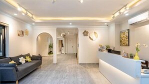 A reception area with a reception desk, a sofa, and a hallway leading to other rooms. - Kelly Hotel SECC Phu My Hung (Ho Chi Minh City)