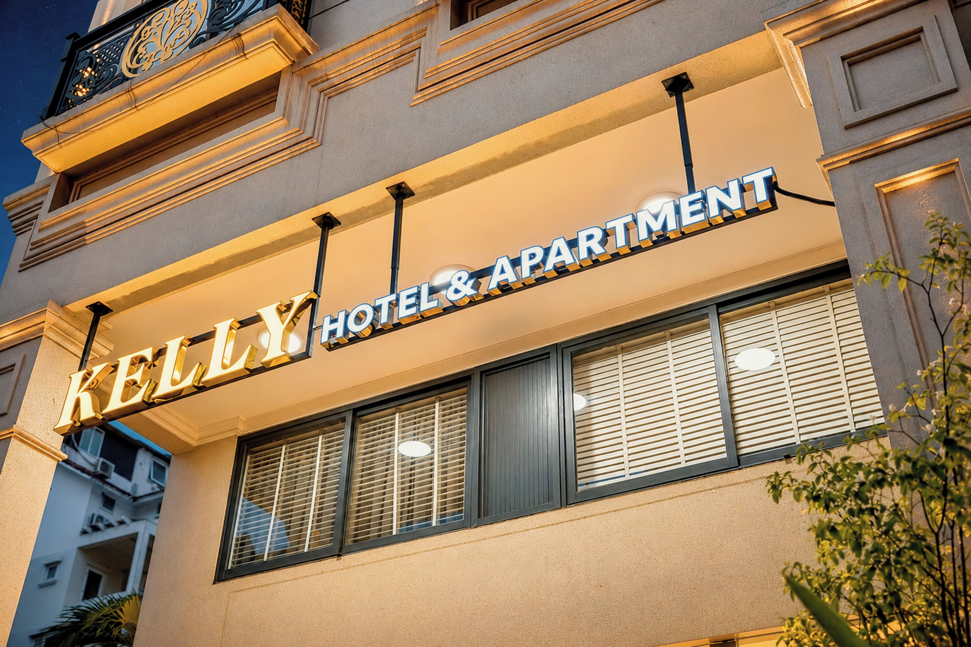 A hotel sign with the name 'KELLY HOTEL & APARTMENT' in illuminated letters.