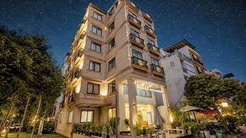 Un hotel con varios pisos, balcones y una entrada bien iluminada.
