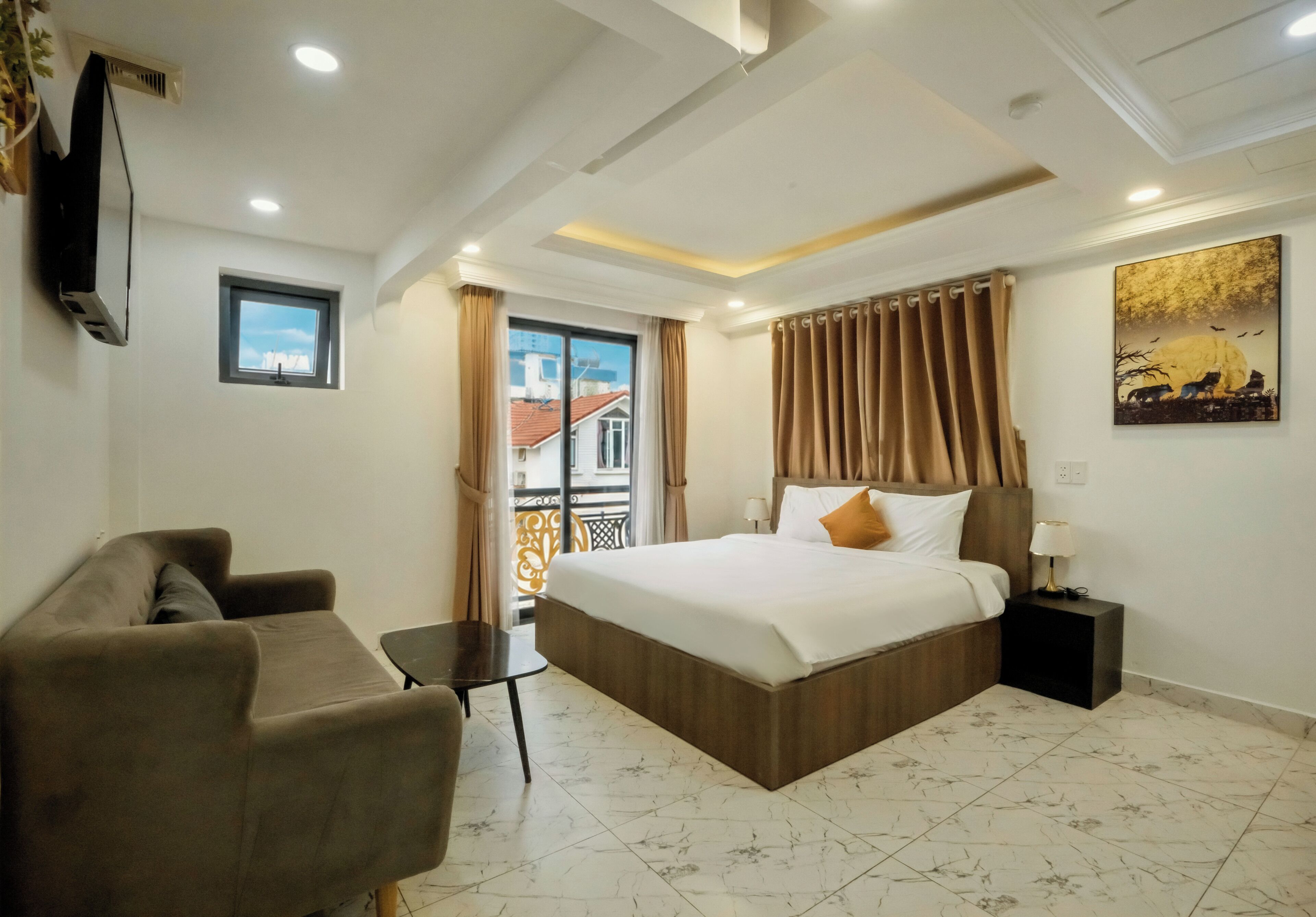 Une chambre d’hôtel avec un lit, un canapé, une petite table, une télévision et une fenêtre avec des rideaux.