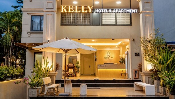 A hotel entrance with a reception desk, a large umbrella, and potted plants. - Kelly Hotel SECC Phu My Hung (Ho Chi Minh City)