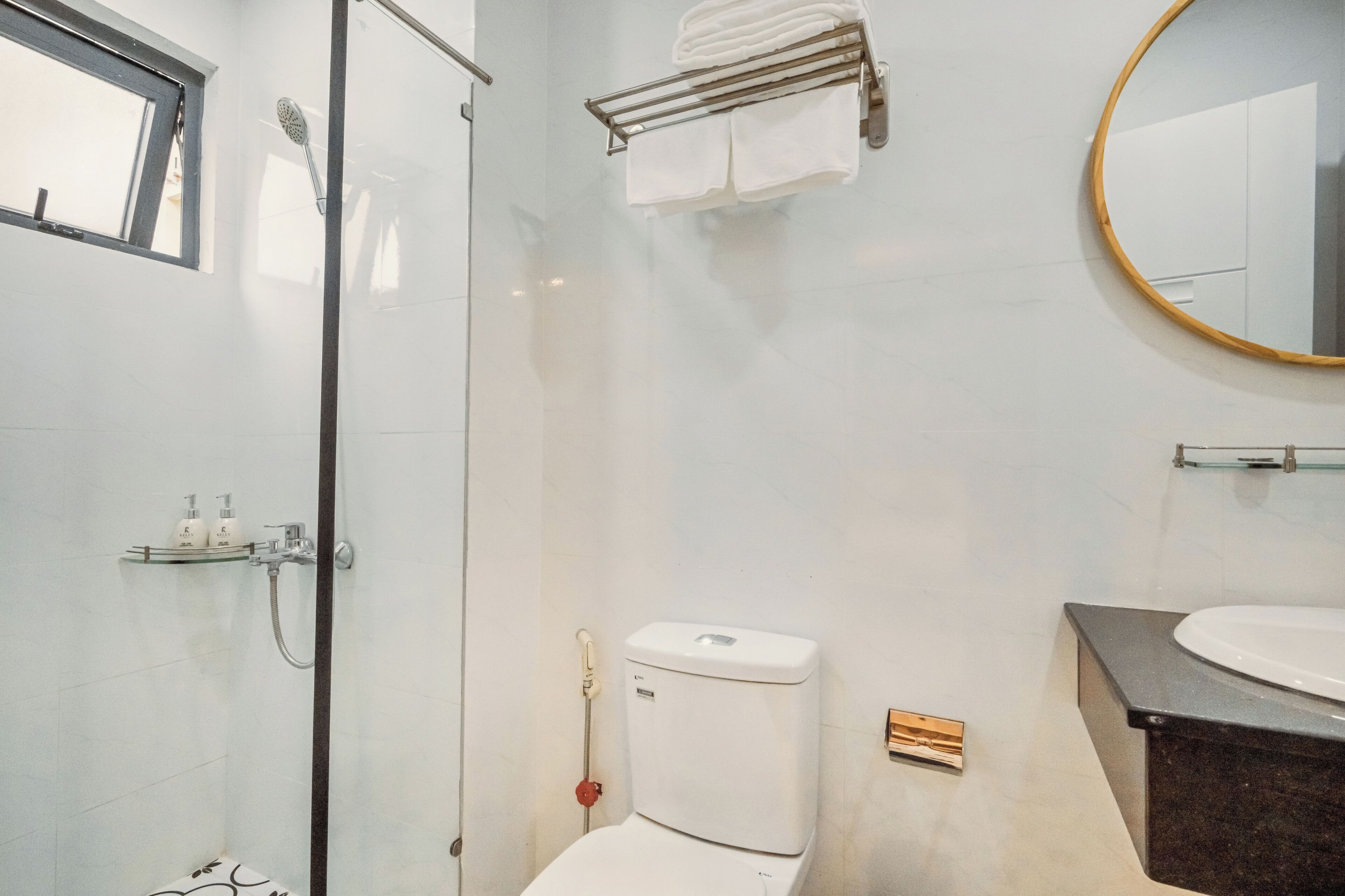 Uma casa de banho moderna com cabine de duche em vidro, sanita, lavatório e porta-toalhas.