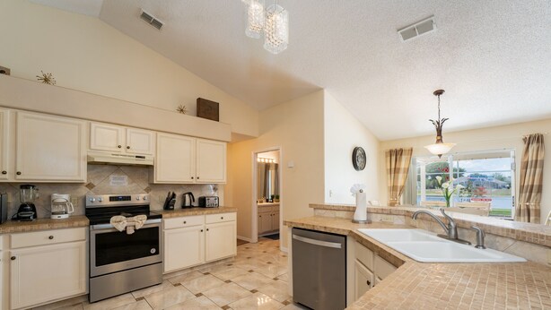 A modern kitchen with white cabinets, stainless steel appliances, and a tiled floor. - Near to Disney/ Large Yard/ Private pool/ Quiet Community (Davenport)