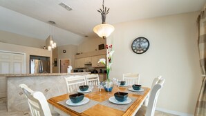 A dining area with a wooden table, white chairs, and blue bowls. - Near to Disney/ Large Yard/ Private pool/ Quiet Community (Davenport)