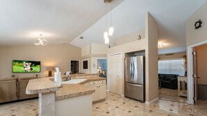 A spacious kitchen with a large island, modern appliances, and a flat-screen TV mounted on the wall. - Near to Disney/ Large Yard/ Private pool/ Quiet Community (Davenport)