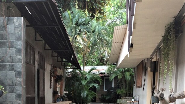 A covered outdoor area with stone flooring, benches, and potted plants. - CRISFILS LODGE INCORPORATED (Dumaguete)