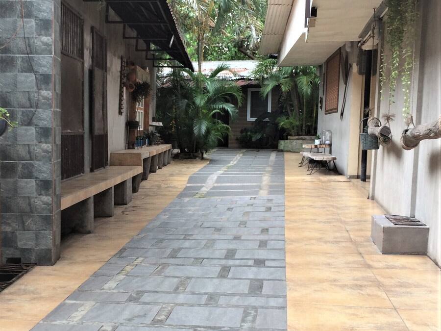 Uma área externa coberta com piso de pedra, bancos e plantas em vasos.