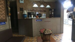 A reception area with a counter, a sign reading "CrisFil's Lodge, Inc.", a flower vase, and a patterned floor. - CRISFILS LODGE INCORPORATED (Dumaguete)
