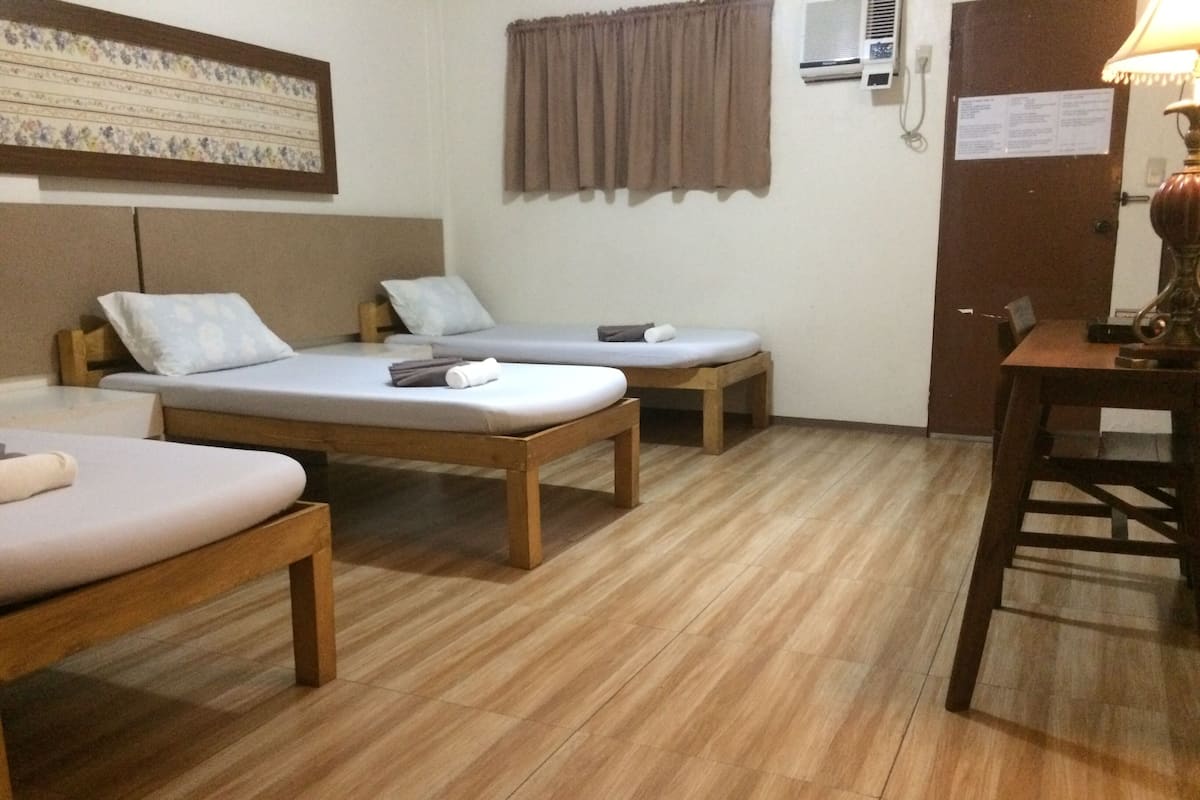 Quarto com duas camas de solteiro, uma mesa de madeira e uma cadeira.