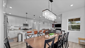Una cucina moderna con mobili bianchi, un tavolo da pranzo in legno e un lampadario.